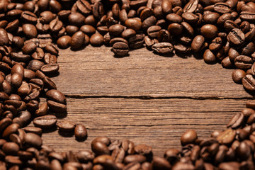 Frame made from roasted coffee Grains over wood background with negative space to place logo or text.