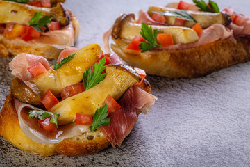 Bruschetta with proscuitto ham, tomatoes and King oyster mushroom. Iitalian style food