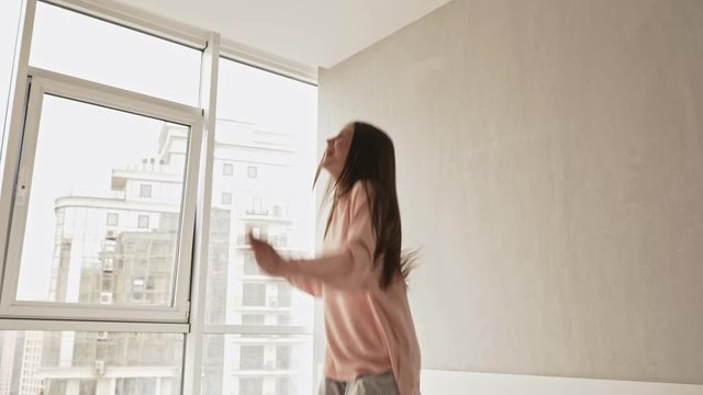 A happy cheerful girl is jumping on the bed at home in the morning