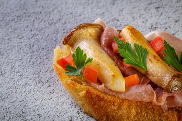 Bruschetta with proscuitto ham, tomatoes and King oyster mushroom. Iitalian style food