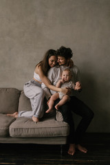 Young beautiful family mom and dad plays with toddler boy son in a living room. Family portrait in...