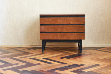 Old antique wardrobe, bedside table stands on a vintage parquet floor. Old apartment design.