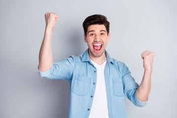 Goal. Photo of crazy funky energetic brunet guy open mouth best feelings watch football match game raise fists wear casual denim shirt isolated grey color background