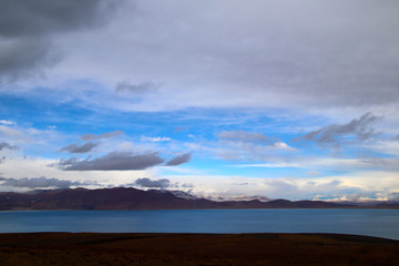 Sunny after the snow, the hut on the pasture, the snowy mountains in the distance, the blue sky and white clouds, the road leading to the distance, the high-voltage power transmission line, the very s