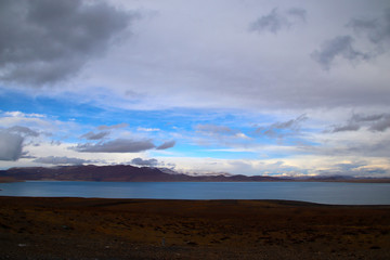 Sunny after the snow, the hut on the pasture, the snowy mountains in the distance, the blue sky and white clouds, the road leading to the distance, the high-voltage power transmission line, the very s