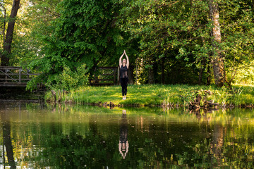 Fototapeta na wymiar Sporty woman doing yoga exercises in different places (in a park in summer) 