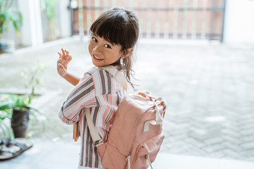young kid waving goodbye before leaving to school in the morning