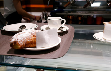 Vassoio con cornetto e cappuccino pronto per essere portato al tavolo da un cliente