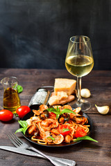 Spaghetti seafood pasta with clams and prawns with mussels and tomatoes in a white plate with on a wooden table. Recipe of Italian cuisine . Top view
