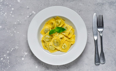 Ravioli with ricotta and spinach in a white plate on a grey stone table. Recipe of Italian pasta, gourmet lunch.  Top view , copy space , food  flat lay