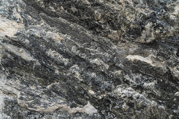 Gold ore texture close-up. Contains quartz, mica, feldspar, chlorite, garnet, carbonate, sulfides and gold. Siberian natural resources deposit. Mineral stone surface abstract background.