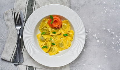 Salmon ravioli traditional Italian food with fresh basil  in a white plate on a grey stone table. Recipe  Italian cuisine, . Top view , copy space , food flat lay