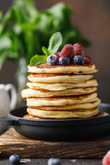 Pancakes with berries and maple syrup. Sweet homemade stack of pancakes