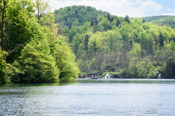 Fototapeta premium Boat sailing on the lake, in the Plitvice Lakes Nature Park, forest reserve located in central Croatia, Europe.