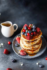 Pancakes with berries and maple syrup. Sweet homemade stack of pancakes