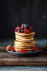 Pancakes with berries and maple syrup. Sweet homemade stack of pancakes