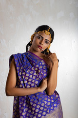 Fototapeta premium Indian girl wearing a traditional blue saree and gold jewellry