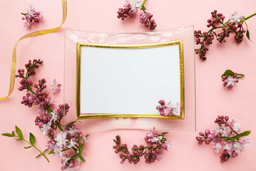 framework for photo or congratulation. lilac branch and photo frame on a pink background