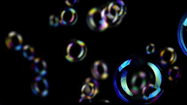 Colorful soap bubbles fly across black background.