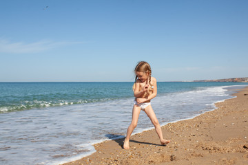 Happy and cheerful child runs on the seashore.