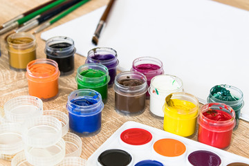 On the table are watercolor paints, brushes and gouache paints. Set for drawing, creativity and...