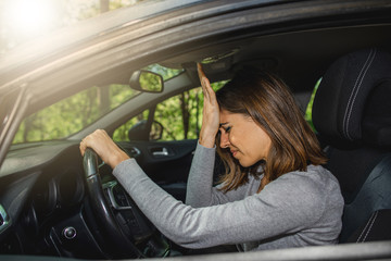 Woman in car putting hands on head after a driving error or a crash.