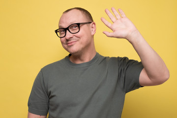 Naklejka premium Friendly looking polite mature man saying hi, waving with his hand