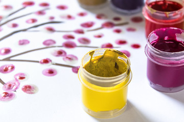 On a white sheet of paper are multi-colored gouache in a jar for drawing. Set for drawing, creativity and hobbies.