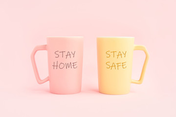 STAY HOME and STAY SAFE written on two cup of coffee on pink background. Healthcare, medical and quarantine concept. Copy space