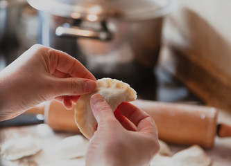 Hands of woman make dumpling pot against background of  pot