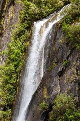 Fototapeta na wymiar A high waterfall on the way to Franz Josef Glacier. South Island, New Zealand