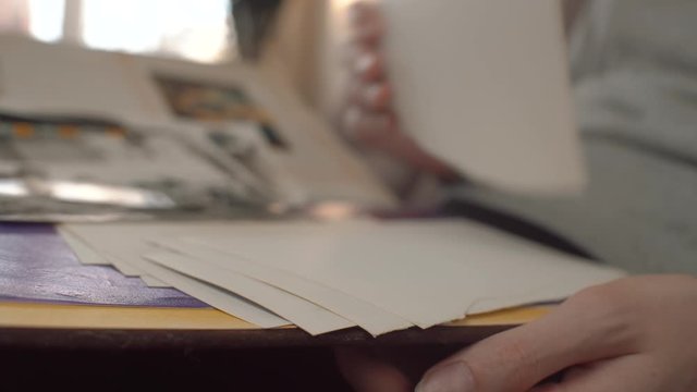 A woman looks at an old photo album, revises photographs and recalls the past.