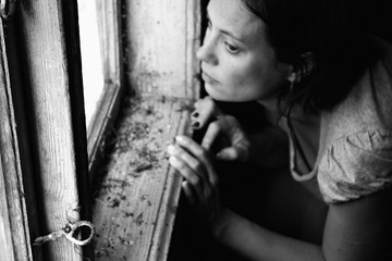 Surreal portrait. Woman looking through the old window. Portrait of a mysterious young woman. Black and white photography. 
