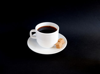 A Cup of black coffee with two sugar cubes on a black background. Suitable for mockups and advertising backgrounds