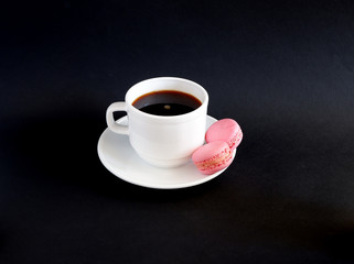 A Cup of black coffee and macaroons on a black background. Suitable for mockups and advertising backgrounds
