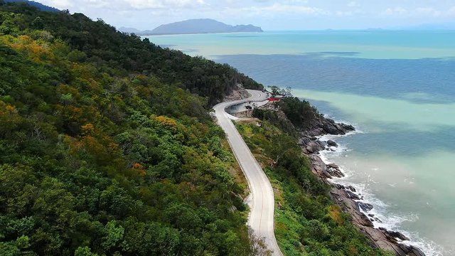 Aerial view of the road beside the blue sea at southern of thailand. with autumn mountain in summer season. smooth drone shot.