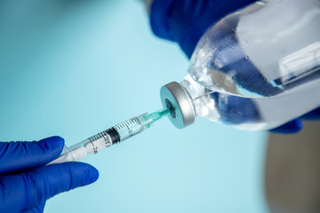 Injection with medication. Vaccine in a syringe. Preparation for injection. Set for injection. A nurse in blue gloves draws medicine into a syringe