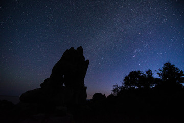 Night mountains view with star sky and full moon of the The petrified forest park in Lakonia, Peloponnese, Greece. View of petrified forest with plant fossils on star sky background.