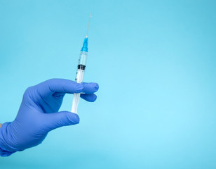 The doctor holds a syringe. Injection with medication. Medical worker in blue gloves. Vaccine in a syringe. Cosmetic procedures. The nurse will give an injection