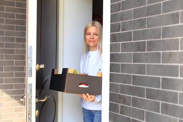 A courier in a protective mask and a glove delivers food to a woman.