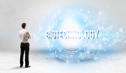 Rear view of a businessman standing in front of BIOTECHNOLOGY inscription, modern technology concept