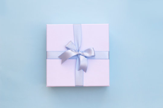 Top view of white gift box with blue ribbon on blue background