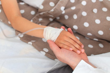 Obraz premium Hands of the doctor who hold the hand of a sick child with a dropper.