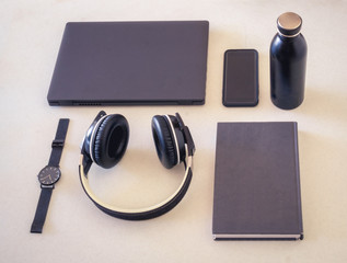 Accesorios organizados en negro y gris en un escritorio como una computadora portátil, un libro,...
