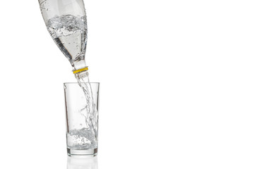 Flowing pure water from plastic bottle into glass on white background