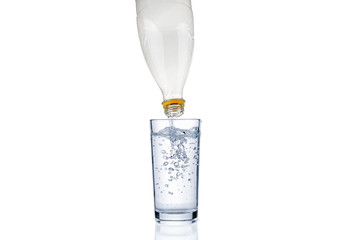 Flowing pure water from plastic bottle into glass isolated on white background