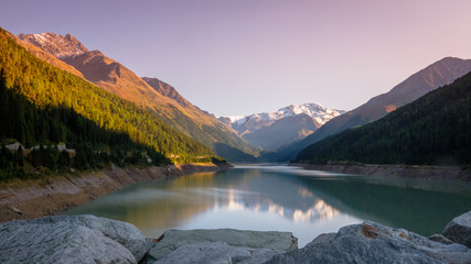 Evening at the gorgeous Gepatsch Reservoir in the Kauner Valley (Tyrol, Austria). This valley features one of the most beautiful mountain roads, the Kauner Valley Glacier Road. - obrazy, fototapety, plakaty