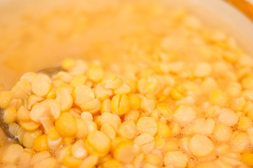 Golden peas in the soaked water. Peas like gold with a spoon in water