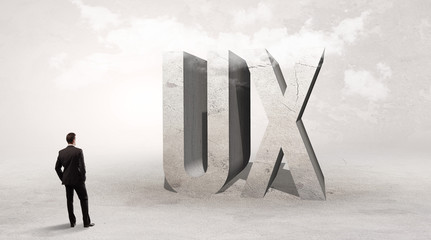 Obraz premium Rear view of a businessman standing in front of UX abbreviation, attention making concept