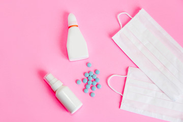 medical protective fabric masks and medications tablets on a pink background